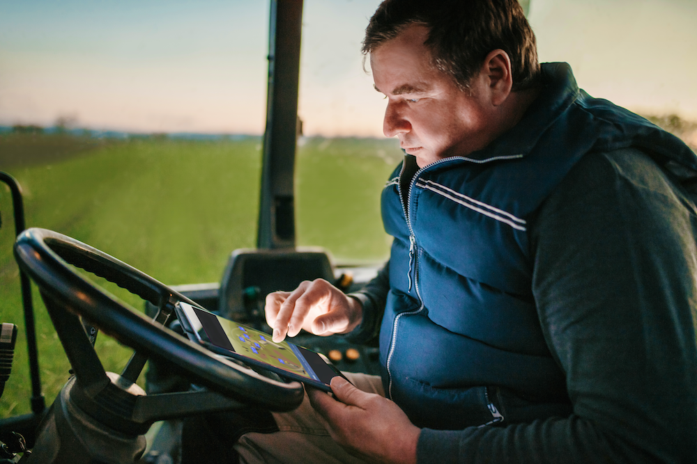 PTx Trimble farmer in cab of tractor on tablet